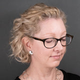 Woman wearing sterling silver button earrings in a mirror finish from Capulin Creations