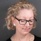 Woman wearing sterling silver button earrings in a satin finish from Capulin Creations