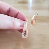 Woman Holding Triangle-Shaped Dangle Earrings in Copper