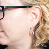Woman wearing triangle-shaped copper dangle earrings stamped with leaves from Capulin Creations