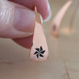 Hand Holding Triangle-Shaped Dangle Earrings in Copper Stamped with Pinwheels