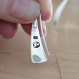 Hand Holding Triangle-Shaped Dangle Earrings in Sterling Silver Stamped with Pinwheels