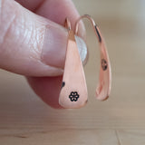 Hand Holding Triangle-Shaped Dangle Earrings in Copper Stamped with Small Flowers