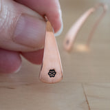 Hand Holding Triangle-Shaped Dangle Earrings in Copper Stamped with Small Flowers