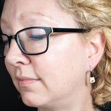 Woman Wearing Triangle-Shaped Dangle Earrings in Copper Stamped with Small Flowers