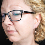 Woman wearing triangle-shaped copper earrings stamped with small spirals from Capulin Creations