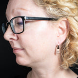 Woman Wearing Triangle-Shaped Dangle Earrings in Copper Stamped with a Solid Heart