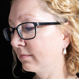 Woman Wearing Triangle-Shaped Dangle Earrings in Sterling Silver Stamped with a Solid Heart