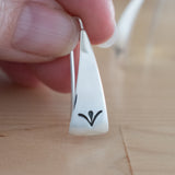 Hand Holding Triangle-Shaped Dangle Earrings in Sterling Silver Stamped with Sprouts