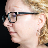 Woman wearing triangle-shaped copper earrings stamped with square spirals from Capulin Creations