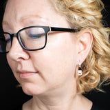 Lifestyle view of triangle-shaped dangle earrings stamped with sunrays in copper from Capulin Creations