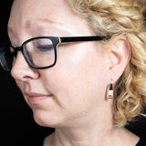 Woman wearing triangle-shaped copper earrings stamped with sunrays from Capulin Creations