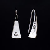 Front and back views of triangle-shaped sterling silver earrings stamped with triple spiral from Capulin Creations