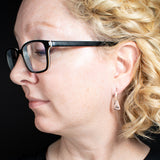 Woman wearing triangle-shaped copper earrings stamped with triple spiral from Capulin Creations