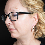 Woman Wearing Triangle-Shaped Dangle Earrings in Copper Stamped with Two Hearts