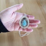 Hand holding larimar and sterling silver pendant necklace from Capulin Creations