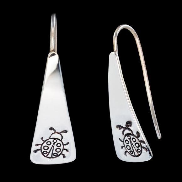 Front and side views of triangle-shaped sterling silver earrings stamped with ladybugs from Capulin Creations