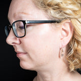 Woman wearing triangle-shaped copper earrings stamped with flowers from Capulin Creations