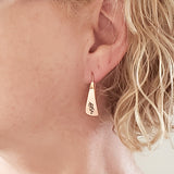 Woman Wearing Triangle-Shaped Dangle Earrings in Copper