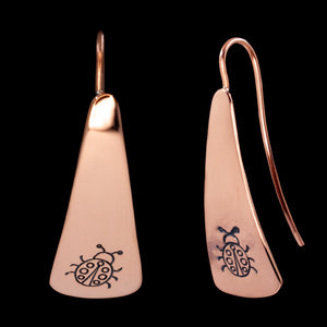 Front and side views of triangle-shaped copper earrings stamped with ladybugs from Capulin Creations
