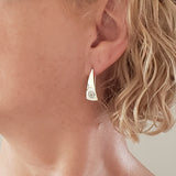 Woman Wearing Triangle-Shaped Dangle Earrings in Sterling Silver Stamped with Large Spirals