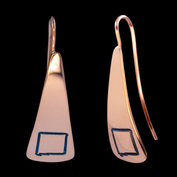 Front and side views of triangle-shaped copper dangle earrings stamped with the outline of the state of New Mexico from Capulin Creations