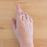 Hand of woman wearing the Opal and Sterling Silver Adjustable Ring with One Stone and One Granule