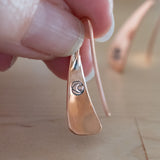 Hand Holding Triangle-Shaped Dangle Earrings in Copper Stamped with Pinwheels