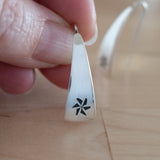 Hand Holding Triangle-Shaped Dangle Earrings in Sterling Silver Stamped with Pinwheels