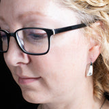 Woman Wearing Triangle-Shaped Dangle Earrings in Sterling Silver Stamped with Pinwheels