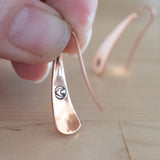Hand Holding Triangle-Shaped Dangle Earrings in Copper Stamped with Small Flowers