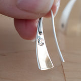 Hand Holding Triangle-Shaped Dangle Earrings in Sterling Silver Stamped with Small Flowers
