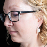 Woman wearing triangle-shaped sterling silver earrings stamped with small spirals from Capulin Creations