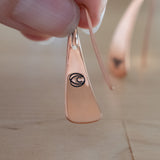 Hand Holding Triangle-Shaped Dangle Earrings in Copper Stamped with Sprouts