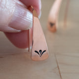 Hand Holding Triangle-Shaped Dangle Earrings in Copper Stamped with Sprouts