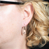 Woman Wearing Triangle-Shaped Dangle Earrings in Copper Stamped with Sprouts