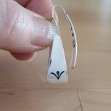 Hand Holding Triangle-Shaped Dangle Earrings in Sterling Silver Stamped with Sprouts