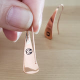 Woman holding Triangle-Shaped Dangle Earrings in Copper stamped with squares