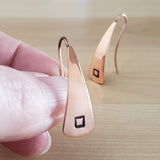 Woman holding Triangle-Shaped Dangle Earrings in Copper stamped with squares