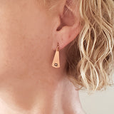 Woman wearing Triangle-Shaped Dangle Earrings in Copper stamped with squares