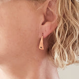 Woman wearing Triangle-Shaped Dangle Earrings in Copper stamped with stars