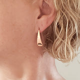 Woman Wearing Triangle-Shaped Dangle Earrings in Copper Stamped with Sunrays