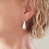 Woman Wearing Triangle-Shaped Dangle Earrings in Sterling Silver Stamped with Sunrays